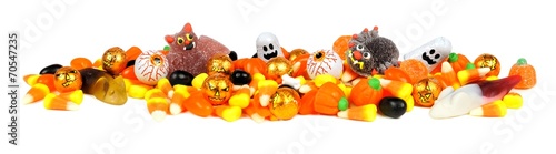 Long border of assorted Halloween candy over white