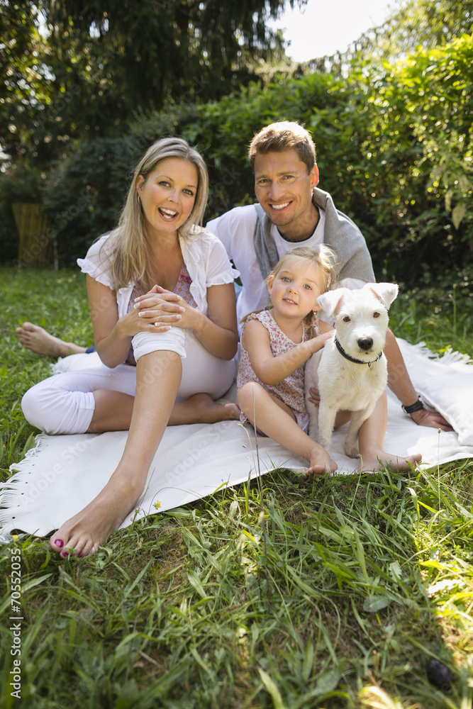 Junge Familie sitzen im Garten mit weisser Jack Russel StockFoto