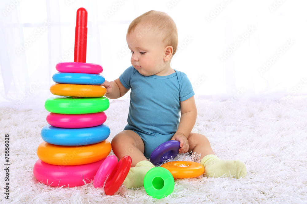 Cute baby boy with plastic pyramid on carpet in room Cute baby boy with plastic pyramid on carpet in room