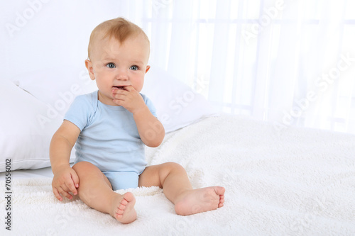 Cute baby boy on bed in room