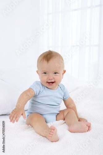 Cute baby boy on bed in room