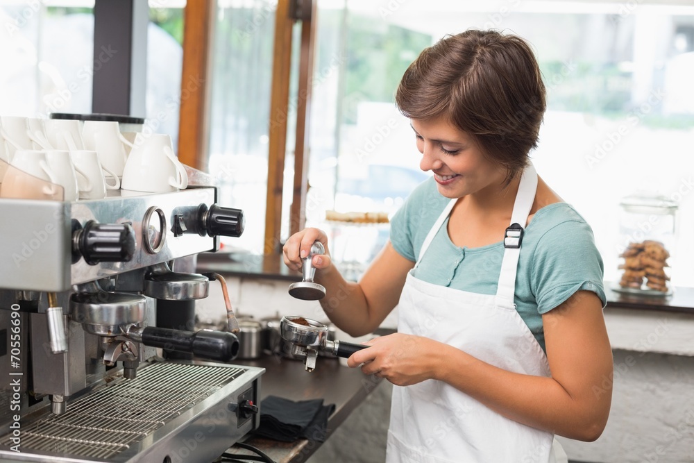 Pretty barista pressing coffee grinds Pretty barista pressing coffee grinds