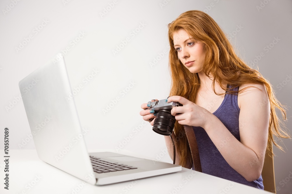 Pretty redhead working on laptop and camera Pretty redhead working on laptop and camera