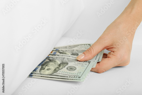 Woman hiding money under pillow at home