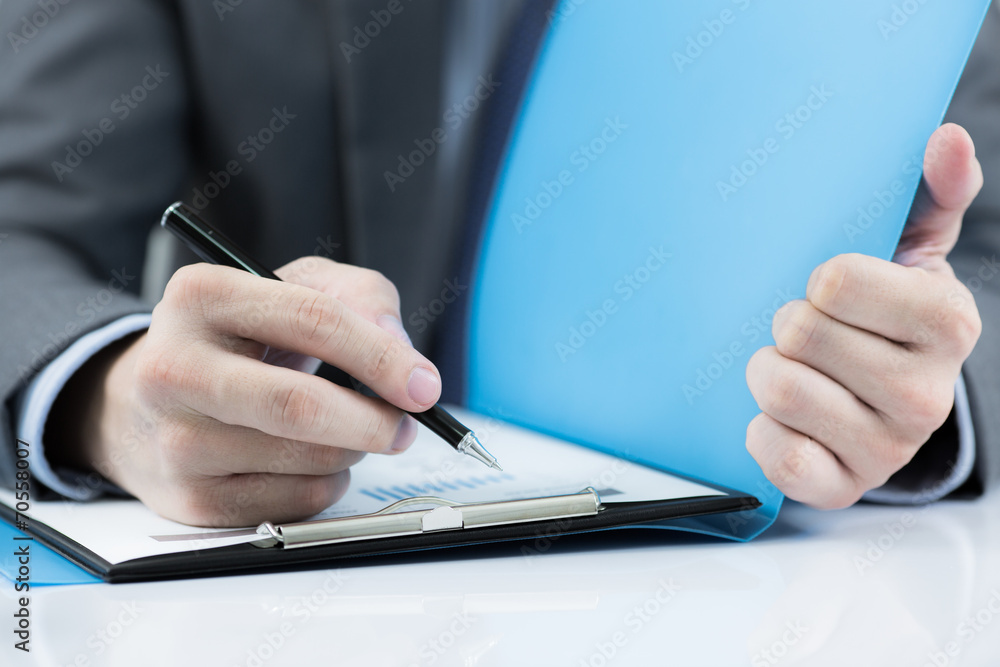 Businessman at the workplace drink coffee and looking some busin Businessman at the workplace drink coffee and looking some busin