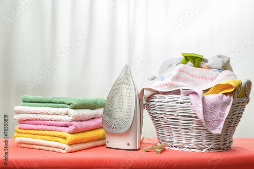 Fotografia White iron and laundry in the white wicker basket on the ironing