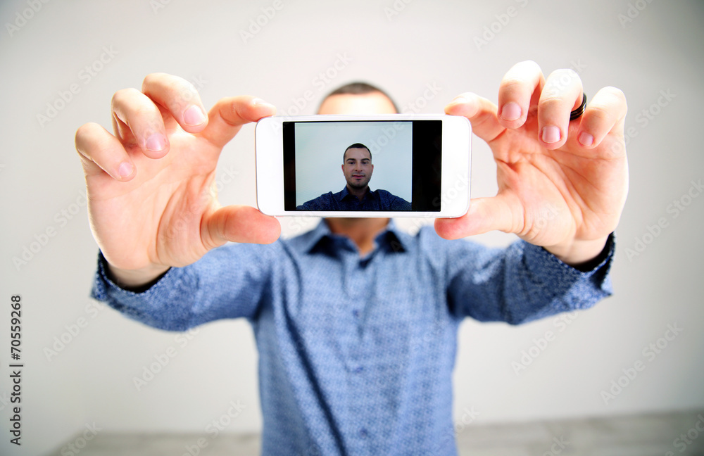 Portrait of a man taking selfie. Focus on smartphone