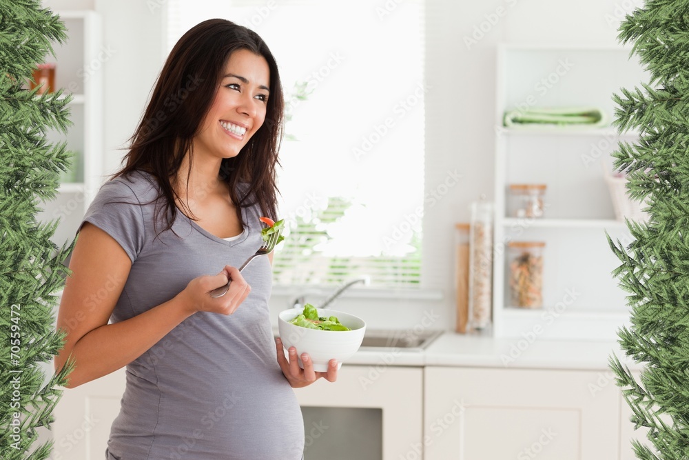 Beautiful pregnant woman holding a bowl of salad while standing Beautiful pregnant woman holding a bowl of salad while standing