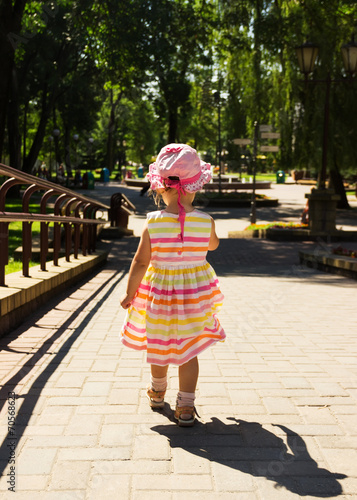 Little girl in beautiful dress running away in the park