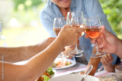 Closeup of wine glasses held by family at lunch