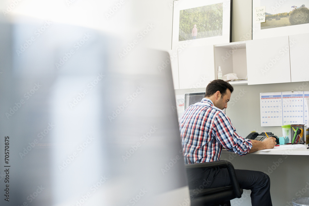 A man working in an office at a desk using a computer. A man working in an office at a desk using a computer.