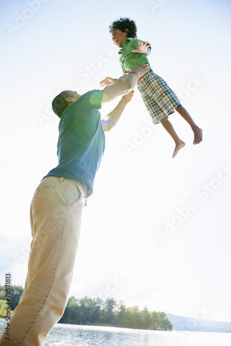 A man lifting a small boy up above his head in play. photo