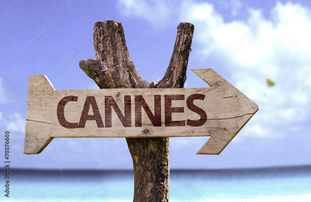 Cannes wooden sign with a beach on background
