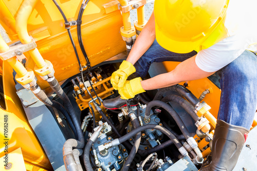 Asian mechanic repairing construction vehicle
