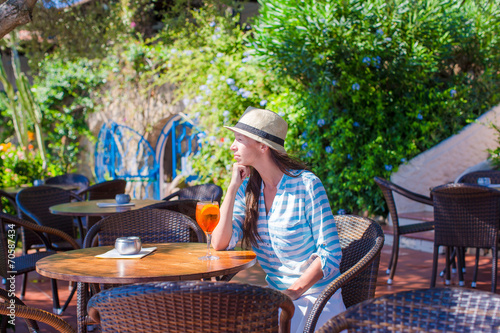 Young woman with cocktail in oitdoor cafe at exotic resort