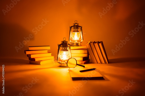 Tableau sur toile Burning kerosene lamps and books, concept magic of light