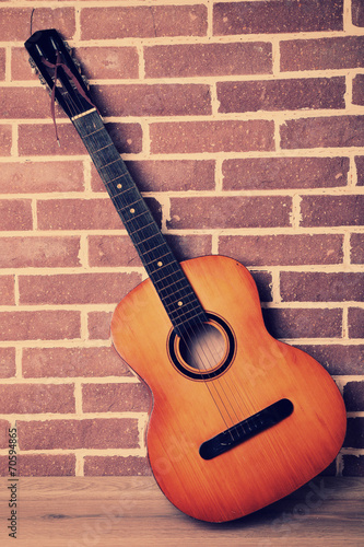 Guitar on floor on brick wall background © Africa Studio