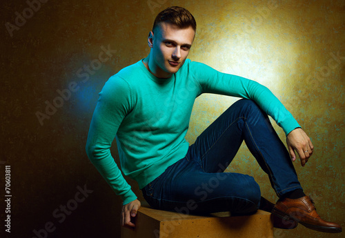 Portrait of handsome stylish man in trendy clothing sitting on c