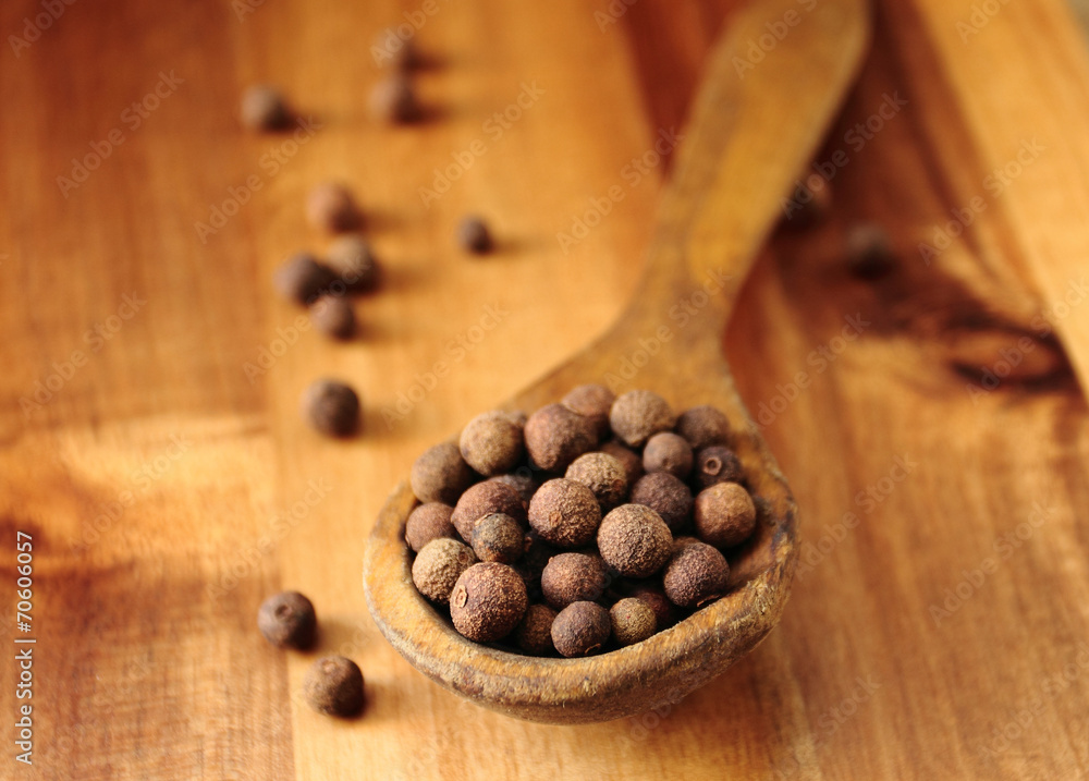 Whole allspice peppers on the old wooden spoon Whole allspice peppers on the old wooden spoon