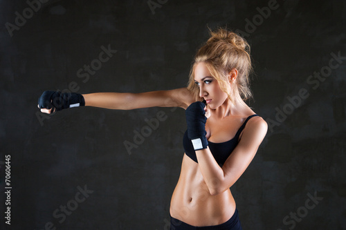 Sexy boxer woman making kick with boxing bandage