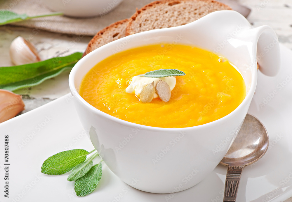 Cream of pumpkin soup with sour cream sauce decorated with a lea Cream of pumpkin soup with sour cream sauce decorated with a lea