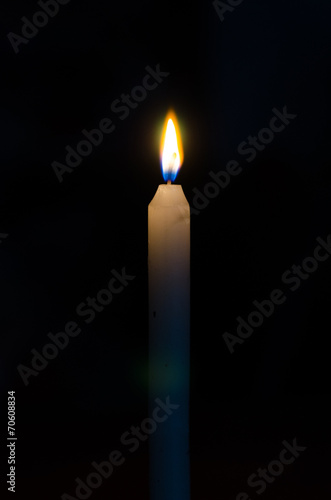 High burning candle on a black background