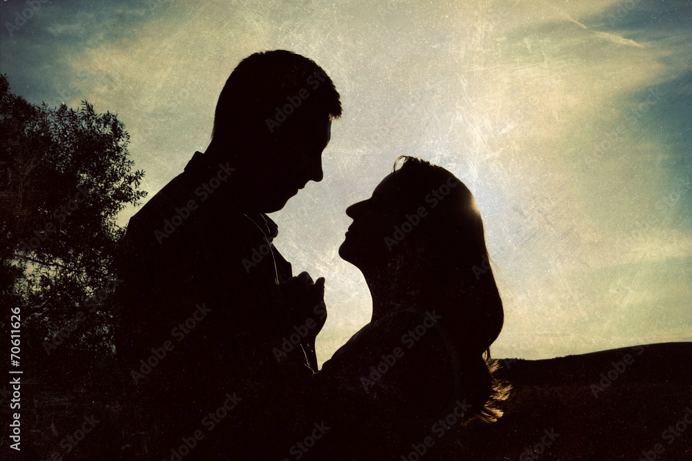 Silhouette of loving couple holding hands in heart shape over or