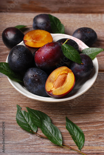 fresh plums in bowl on wooden background