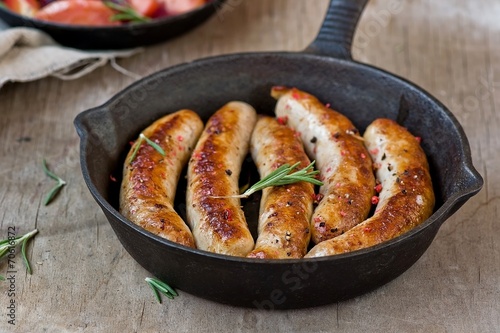 Fotografia fried sausages on a frying pan