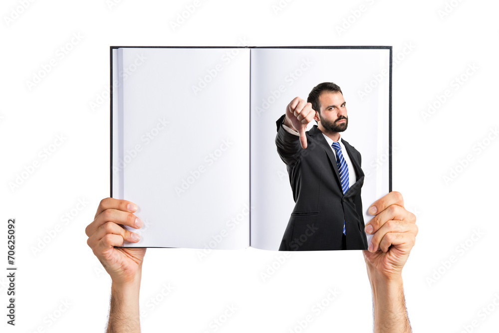 Young businessman with his thumb down printed on book Young businessman with his thumb down printed on book