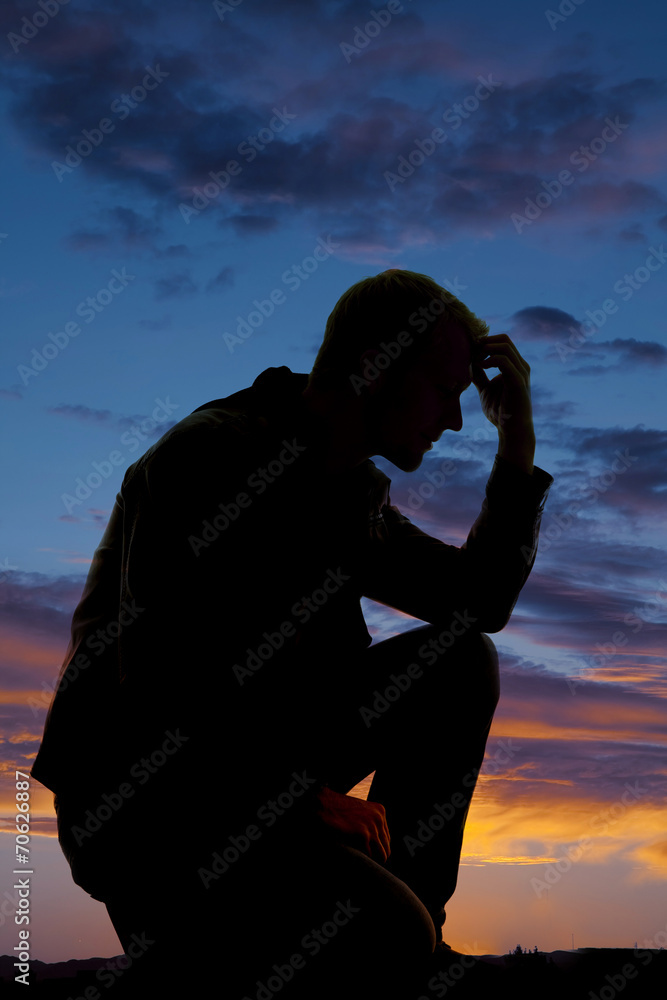 silhouette of man kneel in sunset hand on head