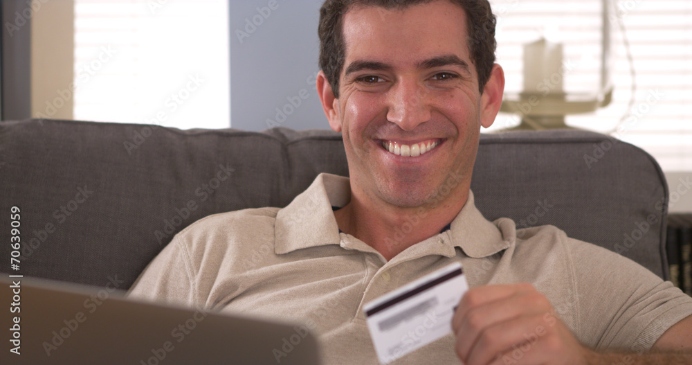 Man smiling with credit card and laptop Man smiling with credit card and laptop