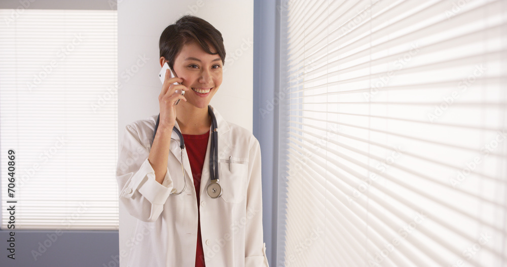 Chinese woman doctor talking on smartphone in office Chinese woman doctor talking on smartphone in office