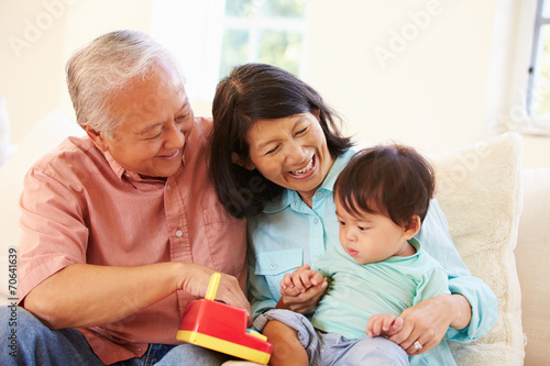 Grandparents And Grandson Playing With Toy Together