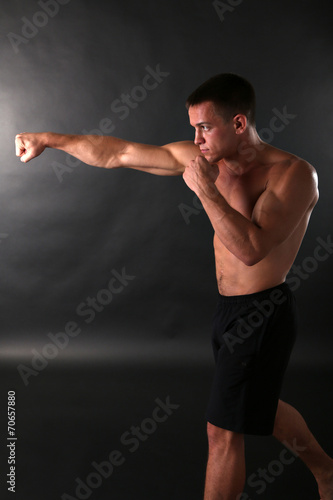 Handsome young muscular sportsman boxing on dark background © Africa Studio