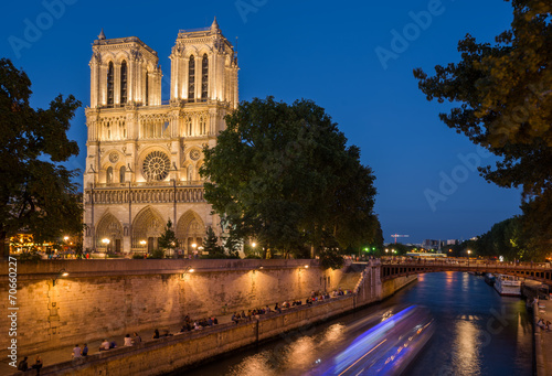 Notre Dame cathedral at dusk with blurred boat lights over Seine