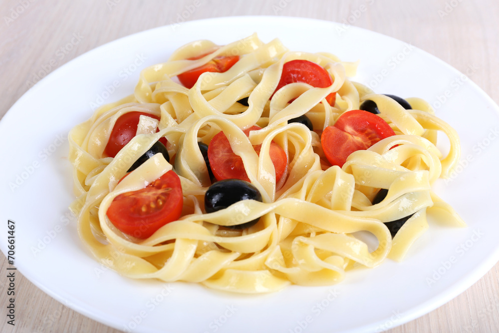 Spaghetti with tomatoes and olives on plate on table Spaghetti with tomatoes and olives on plate on table