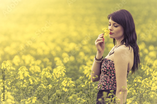 Beautiful woman in meadow of yellow flowers love sniffing flower