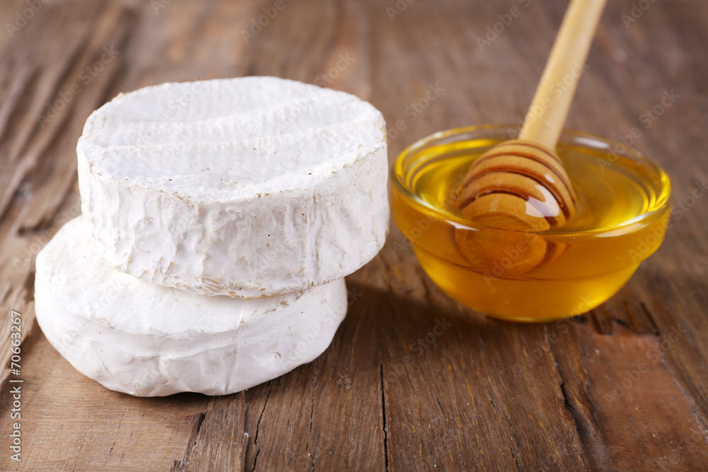 Camembert cheese and honey in glass bowl on wooden background
