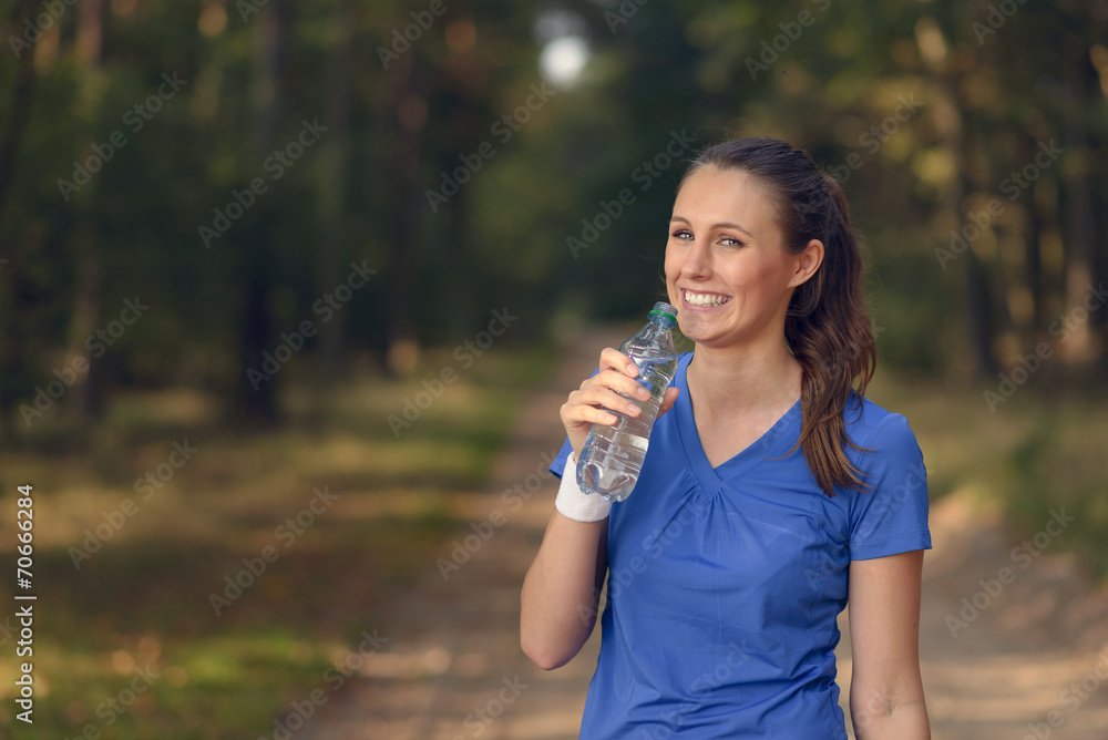 Sportliche junge Frau trinkt aus einer Wasserflasche Sportliche junge Frau trinkt aus einer Wasserflasche