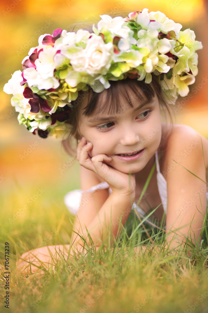 Little girl in autumn wreath of flowers lying on the grass Little girl in autumn wreath of flowers lying on the grass