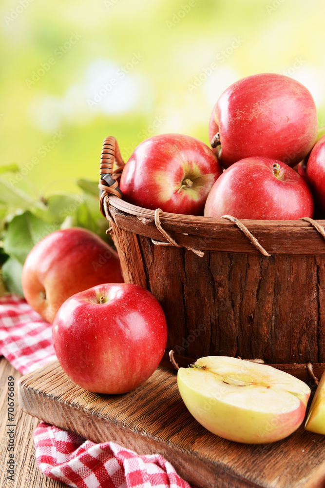 Sweet apples in wooden basket on table on bright background Sweet apples in wooden basket on table on bright background