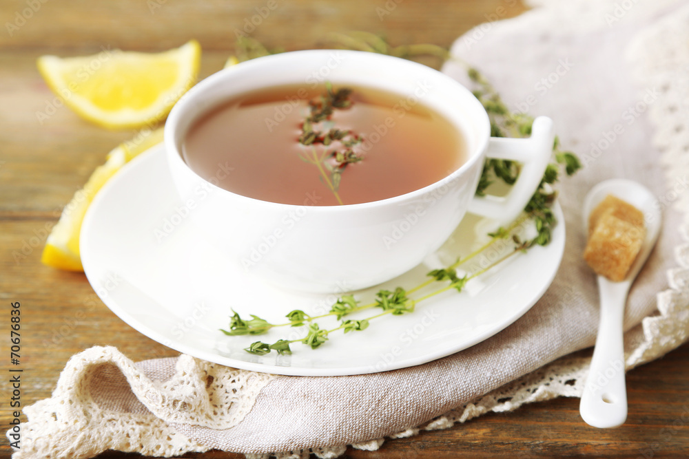 Cup of tasty herbal tea with thyme and lemon on wooden table