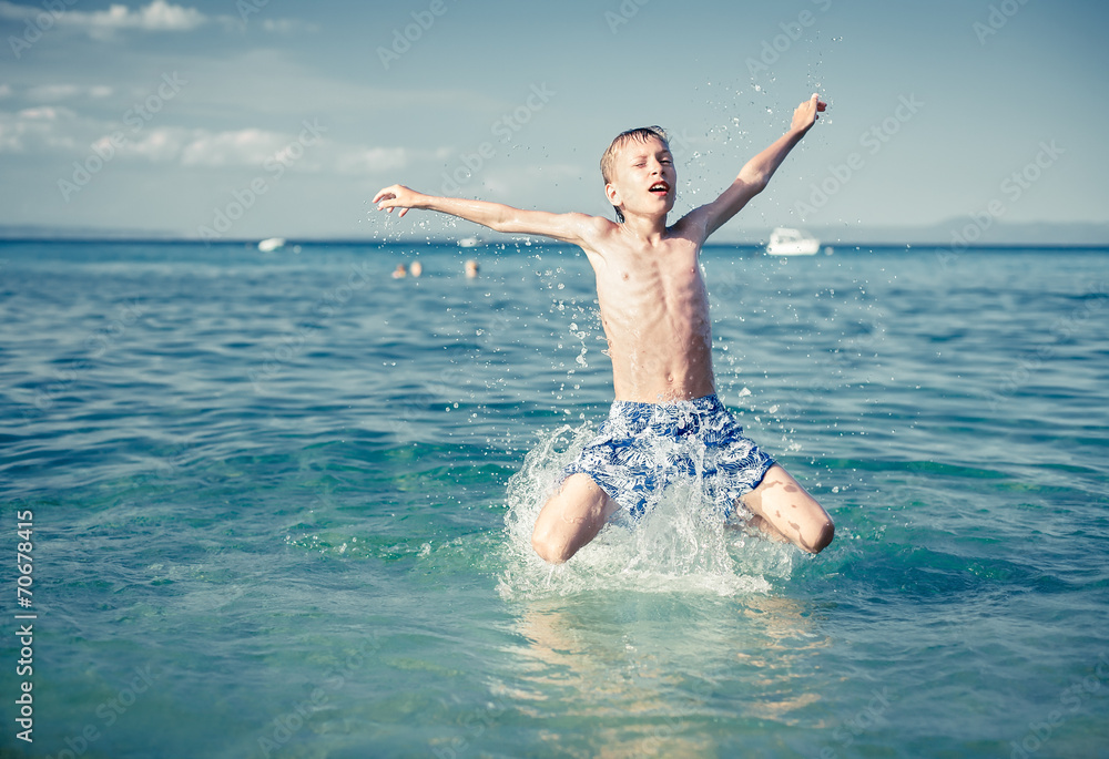 Funny little child playing in sea splashing water and jumping. Funny little child playing in sea splashing water and jumping.