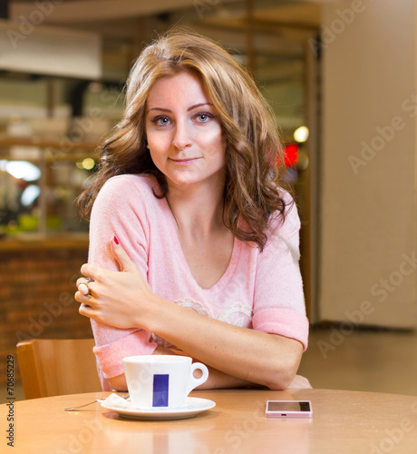 beautiful girl sitting in cafe and drinking coffee