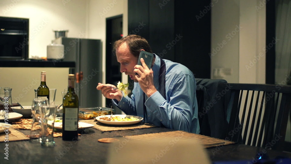 Businessman talking on cellphone, eating dinner at home Businessman talking on cellphone, eating dinner at home