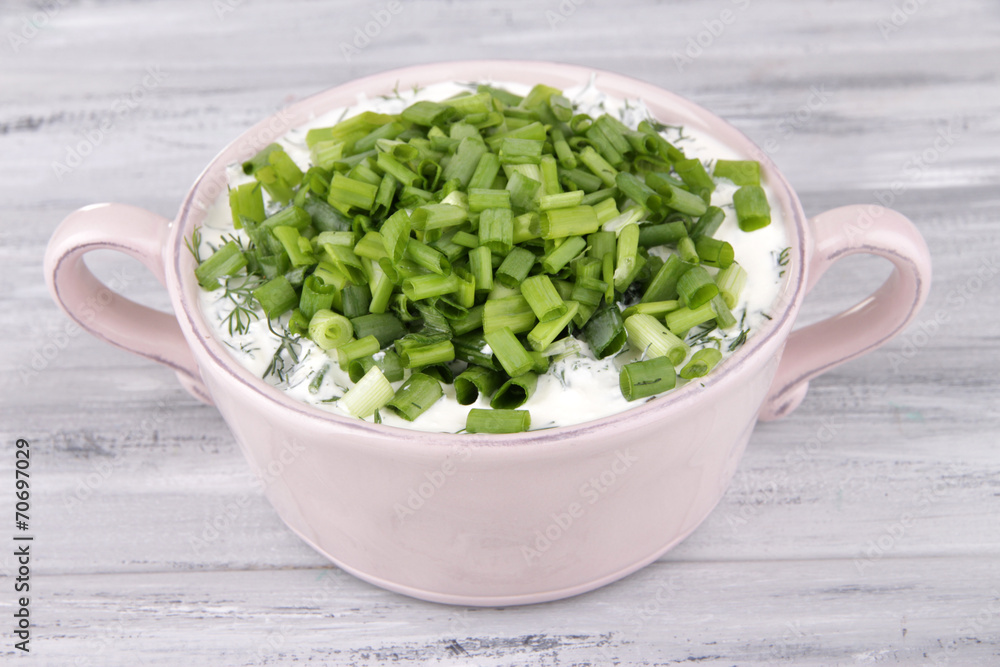 Pink round pan of cream with onion on wooden background