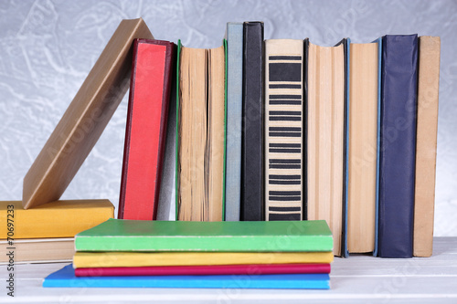 Books on wooden table on light background