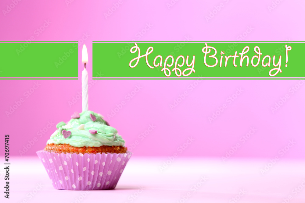 Delicious birthday cupcake on table on pink background Delicious birthday cupcake on table on pink background