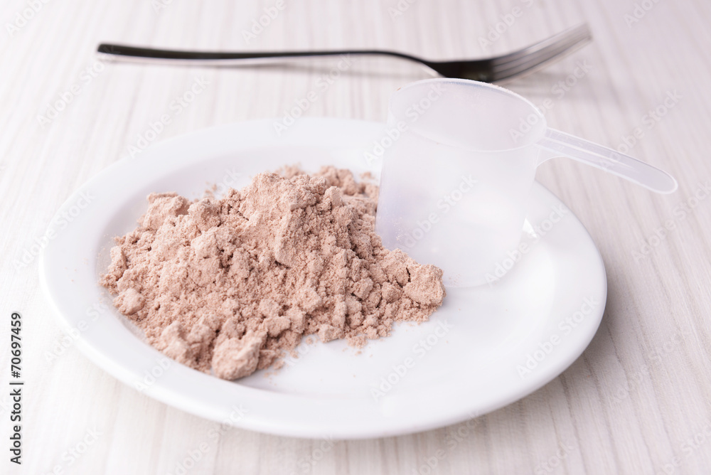 Whey protein powder on plate with scoop on wooden background Whey protein powder on plate with scoop on wooden background
